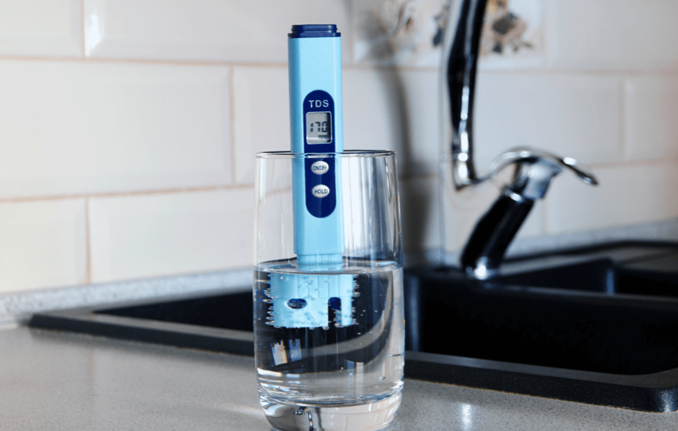 TDS Meter Dipped into Glass of Water on Countertop